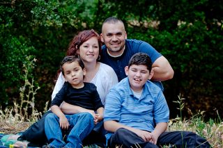 Portrait of family of four in the park, one child has a developmental disability.