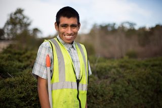 Young man with autism poses during landscape work with his team.