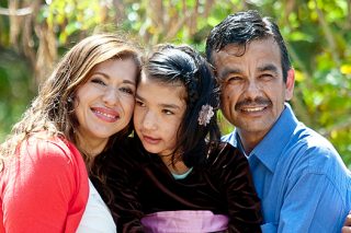 Mom and dad hold daughter with development disabilities in the park.