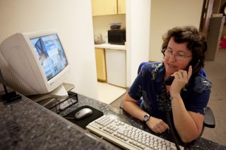 A woman with special needs answers the phone at her office assistant job.