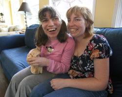 Nicole Cantrell sits with a women she helps support. They both have big smiles.