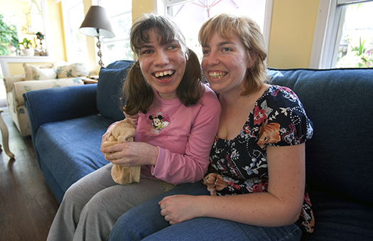 Nicole Cantrell sits with a women she helps support. They both have big smiles.