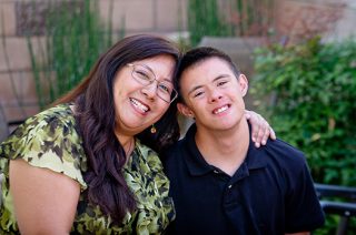 Mother smiling with her smiling teenage son that has a developmental disability.