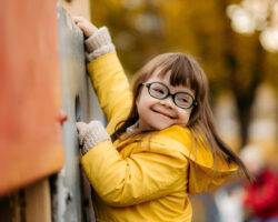 Happy child with down syndrome enjoying swing on playground