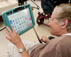 Senior woman uses an assistive tech device at her day program