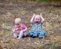 Adorable toddler sitting on the ground making a silly, open mouth gesture