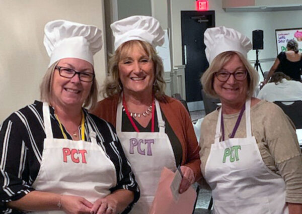 Three TCRC staff and service providers wear "PCT" aprons and chef hats at the California Gathering