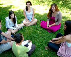 Small group discussion sitting in a circle at the park, smiling