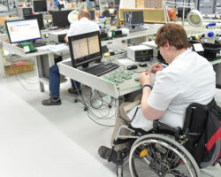 Employee with disabilities is on the job repairing motherboards