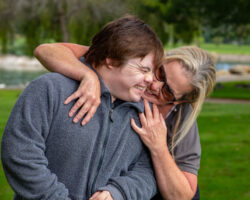 Mom hugs her young adult with Down Syndrome