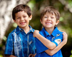 Young brothers Billy and Marko give toothless smiles to the camera while Marko hugs himself