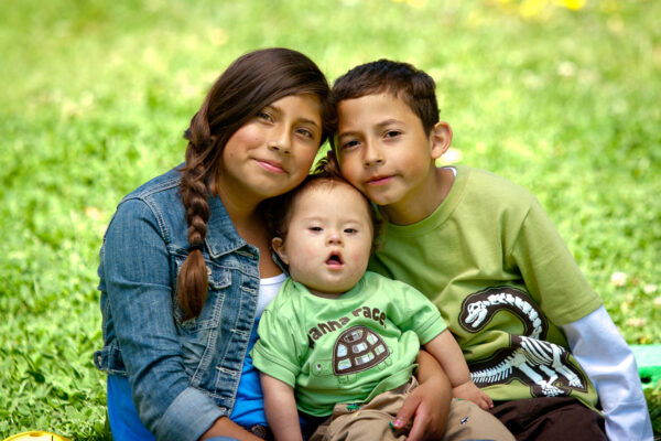 Two young siblings hold their infant brother who has Down Syndrome