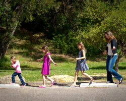 Mom and three daughters balance on parking curbs in parking lot