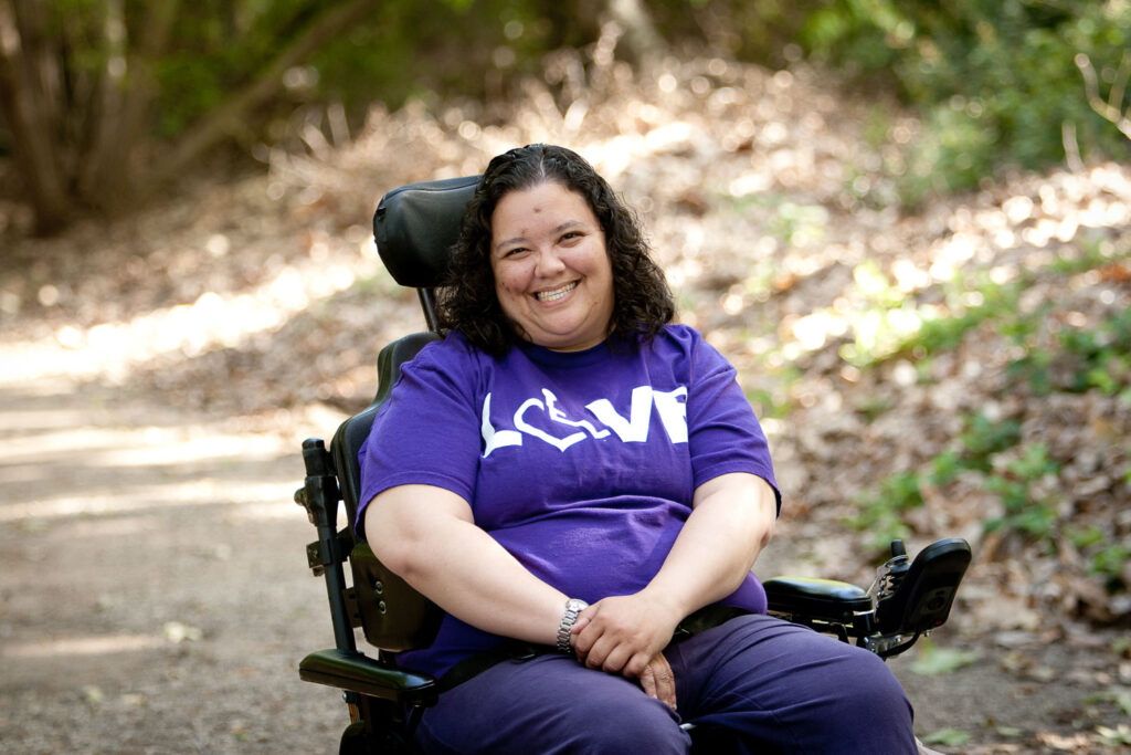 Young adult woman who uses a wheelchair smiles for a photo