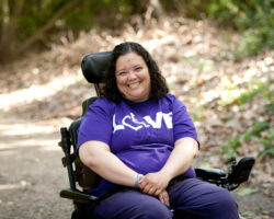 Young adult woman who uses a wheelchair smiles for a photo