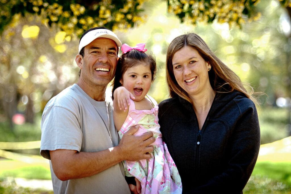 Dad and mom hold toddler with down syndrome