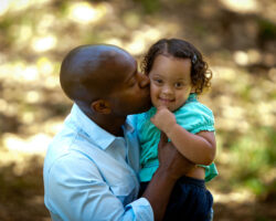 Black dad holds young daughter with Down Syndrome