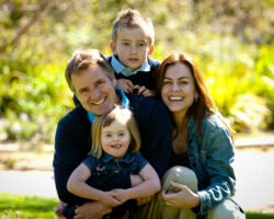 Family of four of European descent pose in the park