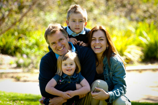 Family of four of European descent pose in the park