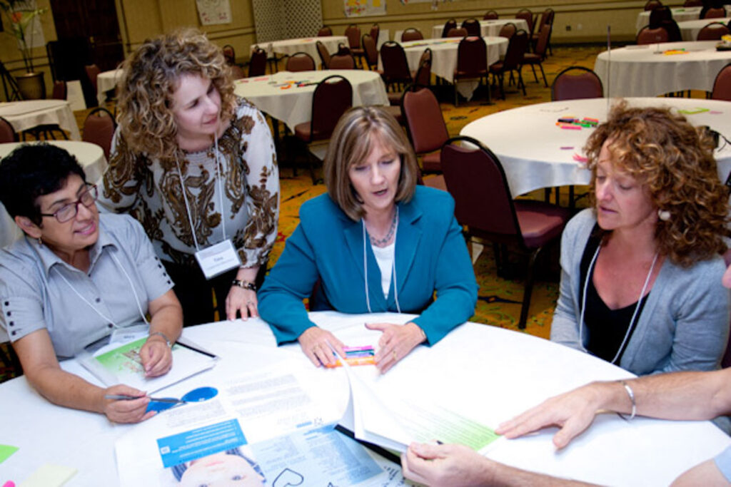 TCRC staff and stakeholders sit at a round event table discussing training