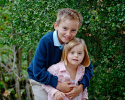 Brother hugs little sister who has down syndrome