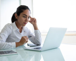 Hispanic service provider looks at laptop in her office