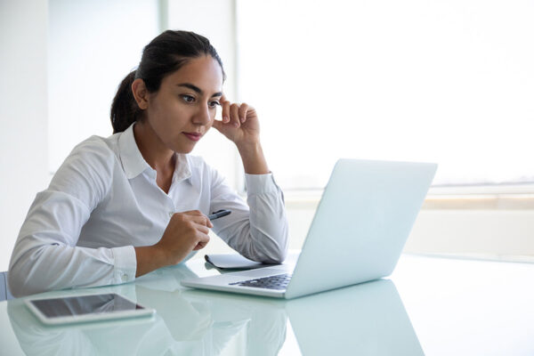 Hispanic service provider looks at laptop in her office