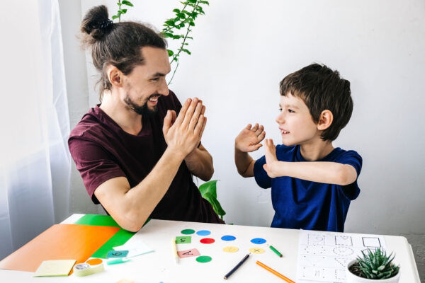 Happy boy with autism during therapy with school counselor, learning and having fun together