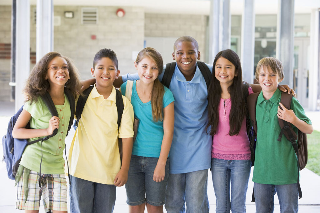 Six students standing outside school together smiling