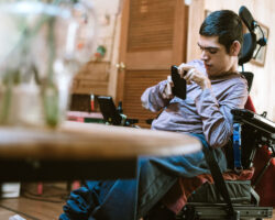 Man with cerebral palsy sits in his dining room working on his phone