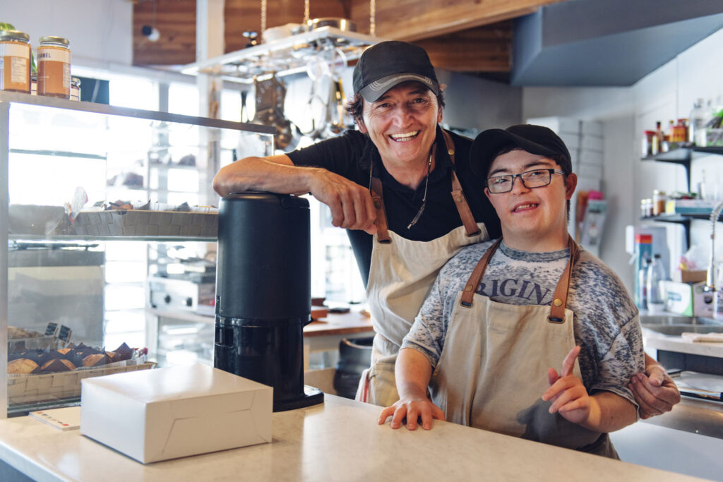 Young employee with disabilities stands with the business owner in the shop