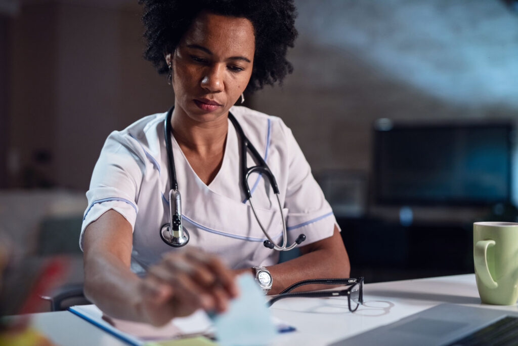 black nurse reviews paperwork at her desk