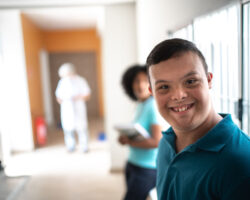 A special needs student turns and smiles in the school hallway