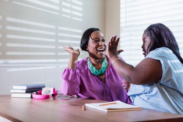 Black service provider gives high five to young woman with down syndrome