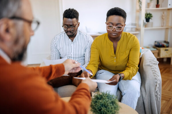 Black couple look at paperwork handed to them by a Service Coordinator