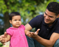 Father helping his toddler daughter to walk in the park