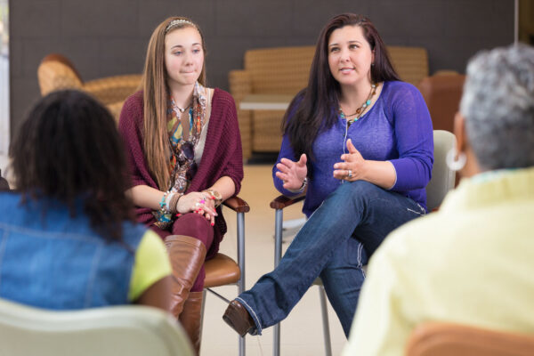 Two women sitting in support group circle, sharing.