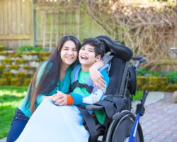 Teen sister hugs her younger brother with cerebral palsy