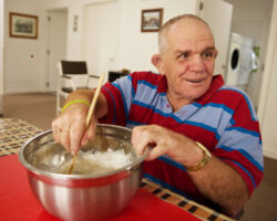 Older man with a disability mixing flour for a meal in his home