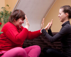 Two women, one of them disabled, playing "patty-cake" for a rhythm exercise