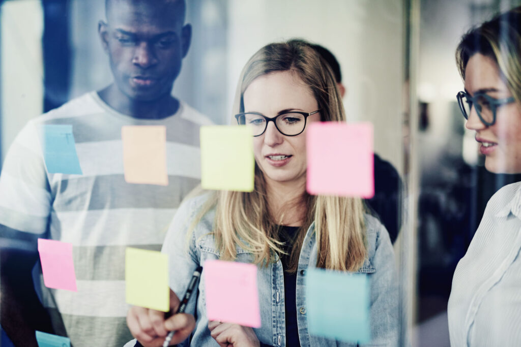 Group of stakeholders re-arrange sticky notes as they form their thought on the topic at hand