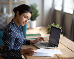 Young female Service Provider sitting with her laptop and looking at notes