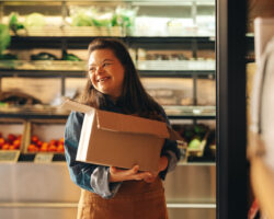 Woman with Down syndrome smiling happily while working as a shopkeeper in a grocery store.