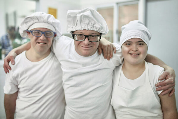 three individuals served by regional centers at work together in a bakery