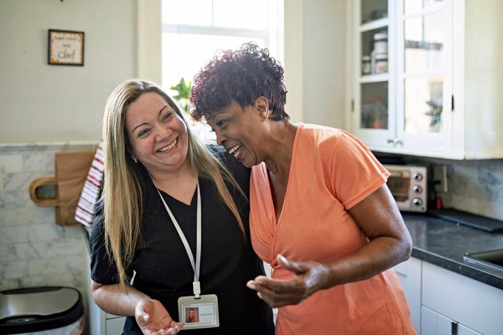 two social workers hug and smile in a kitchen