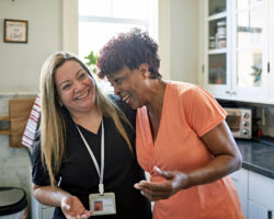 two social workers hug and smile in a kitchen